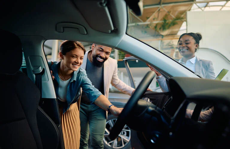 happy-multiracial-couple-looking-at-new-car-in-sho-2023-11-28-04-23-53-utc (1)